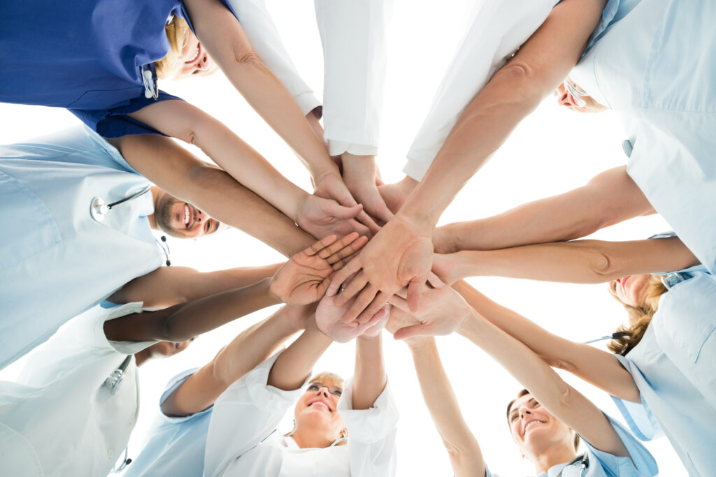 Symbolfoto Teamwork viele Menschen legen ihre Hände übereinander