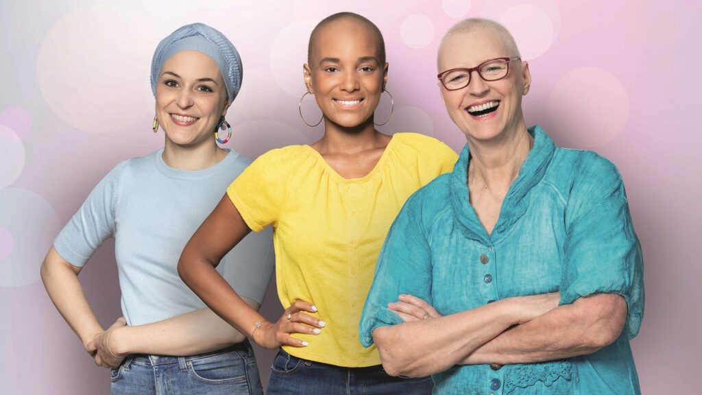 Frauen, die durch Haarausfall als Patientinnen zu erkennen sind, lachen in die Kamera